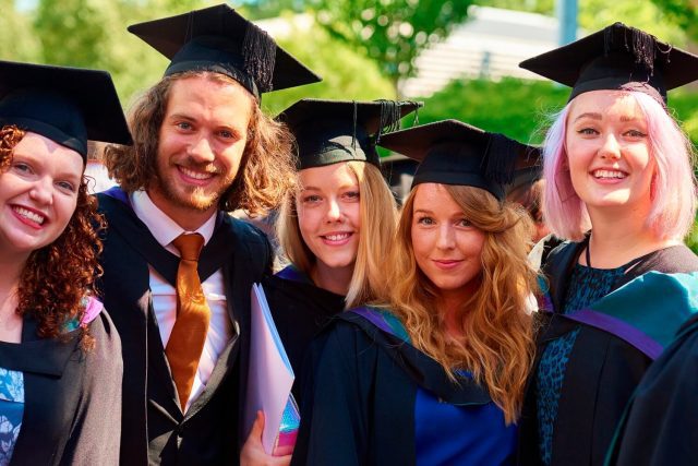 Five students in cap and gowns on their graduation day.