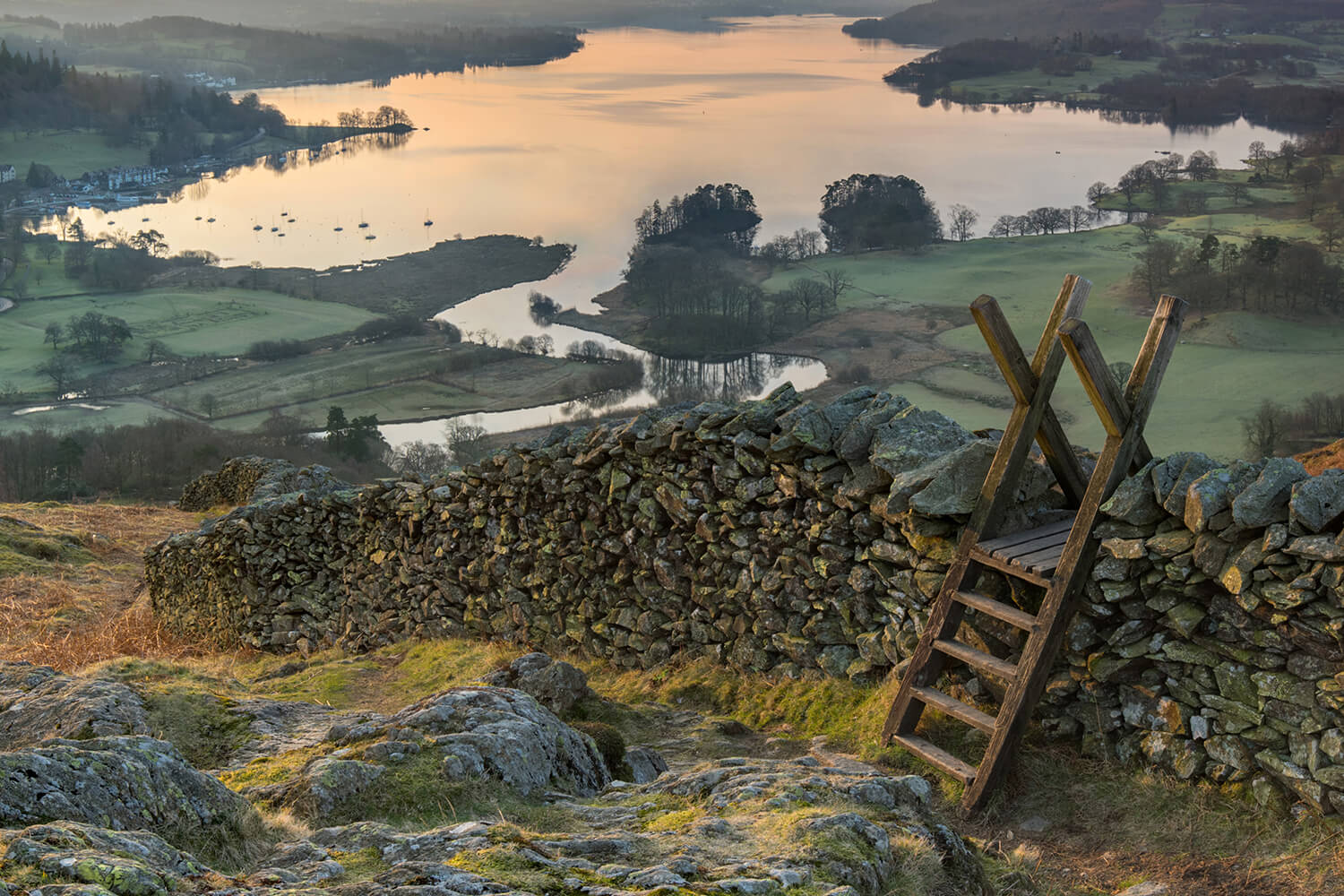 A style over a dry-stone wall overlooking a lake in the Lake District.