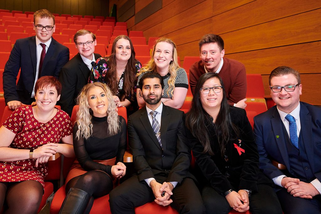 Ten students sit in a lecture theatre while attending a Scholarship Awards Evening to celebrate their success.