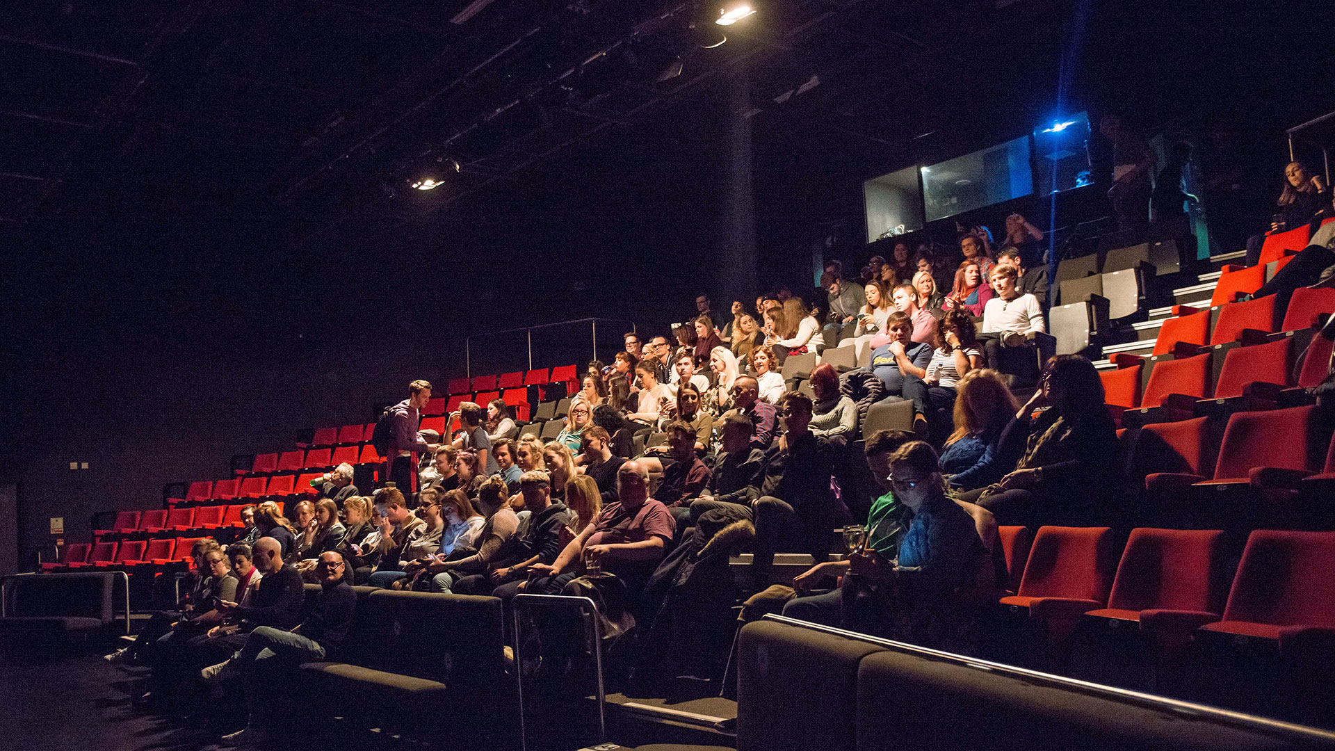 A crowd sits in one of our on-campus theatres, watching a performance