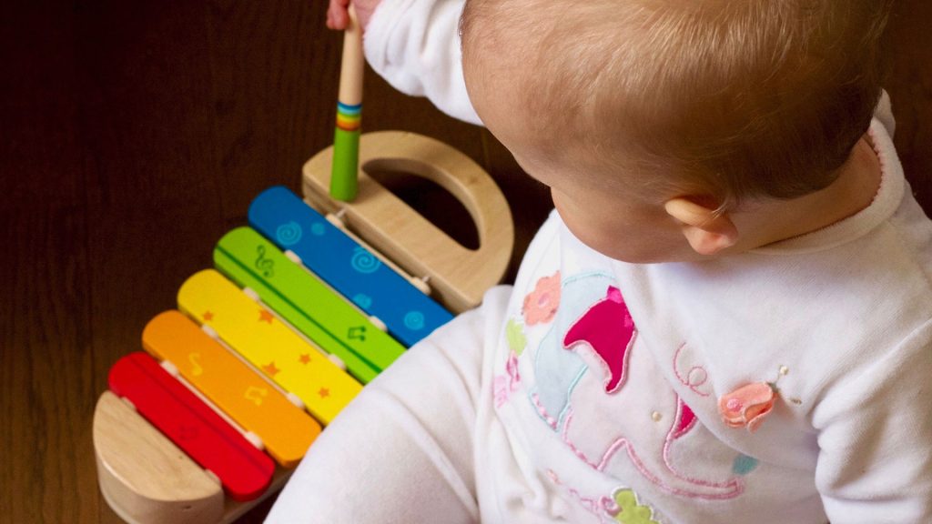 A baby is playing on a musical instrument toy