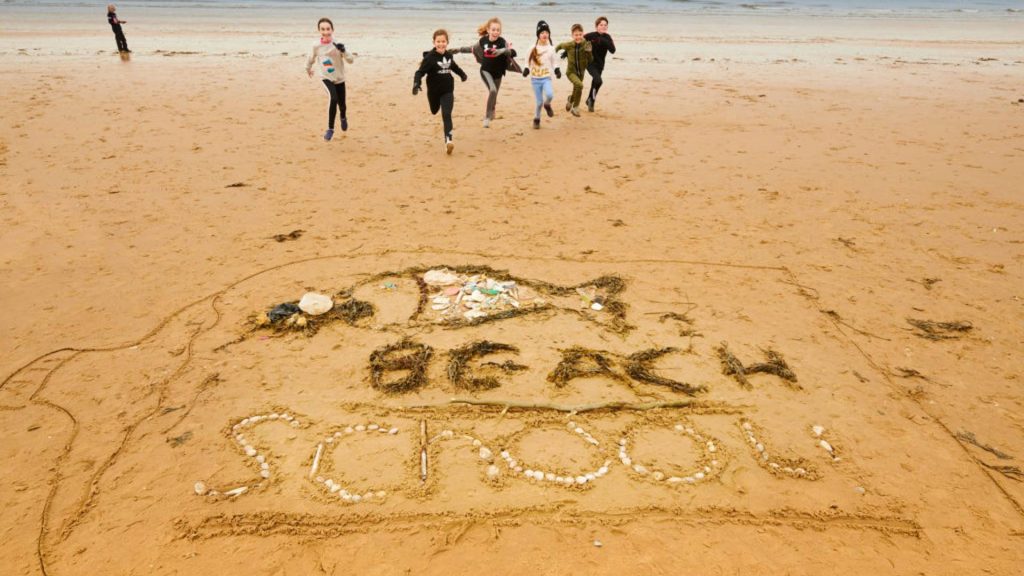 Children on Formby Beach with Beach School written in the sand