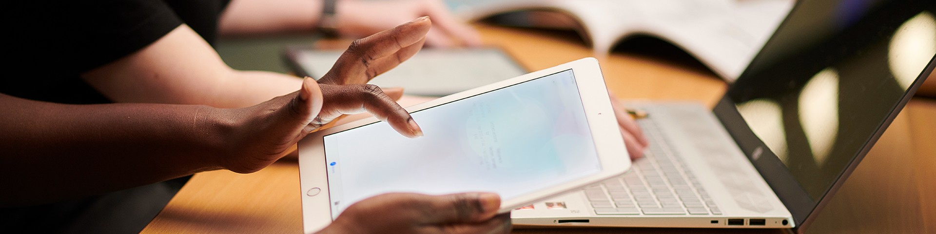 Hands using an ipad and laptop