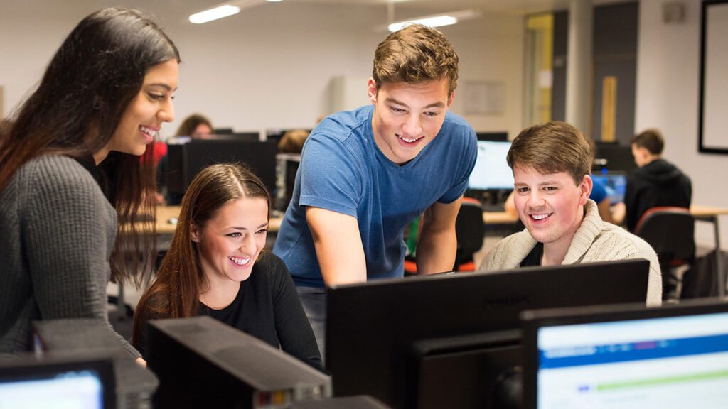 Computing students crowded around a computer.