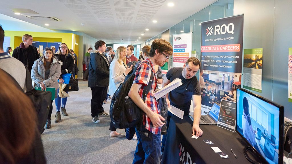 Students at a computing careers fair, chatting to staff manning information stands