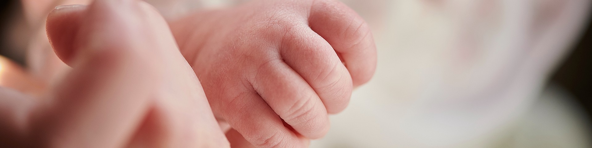 Mother holding newborn baby's hand