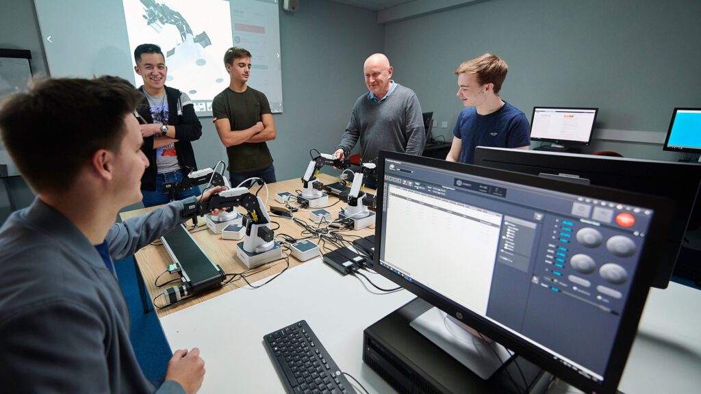 BEng Electronic Engineering students and staff sit at a computer