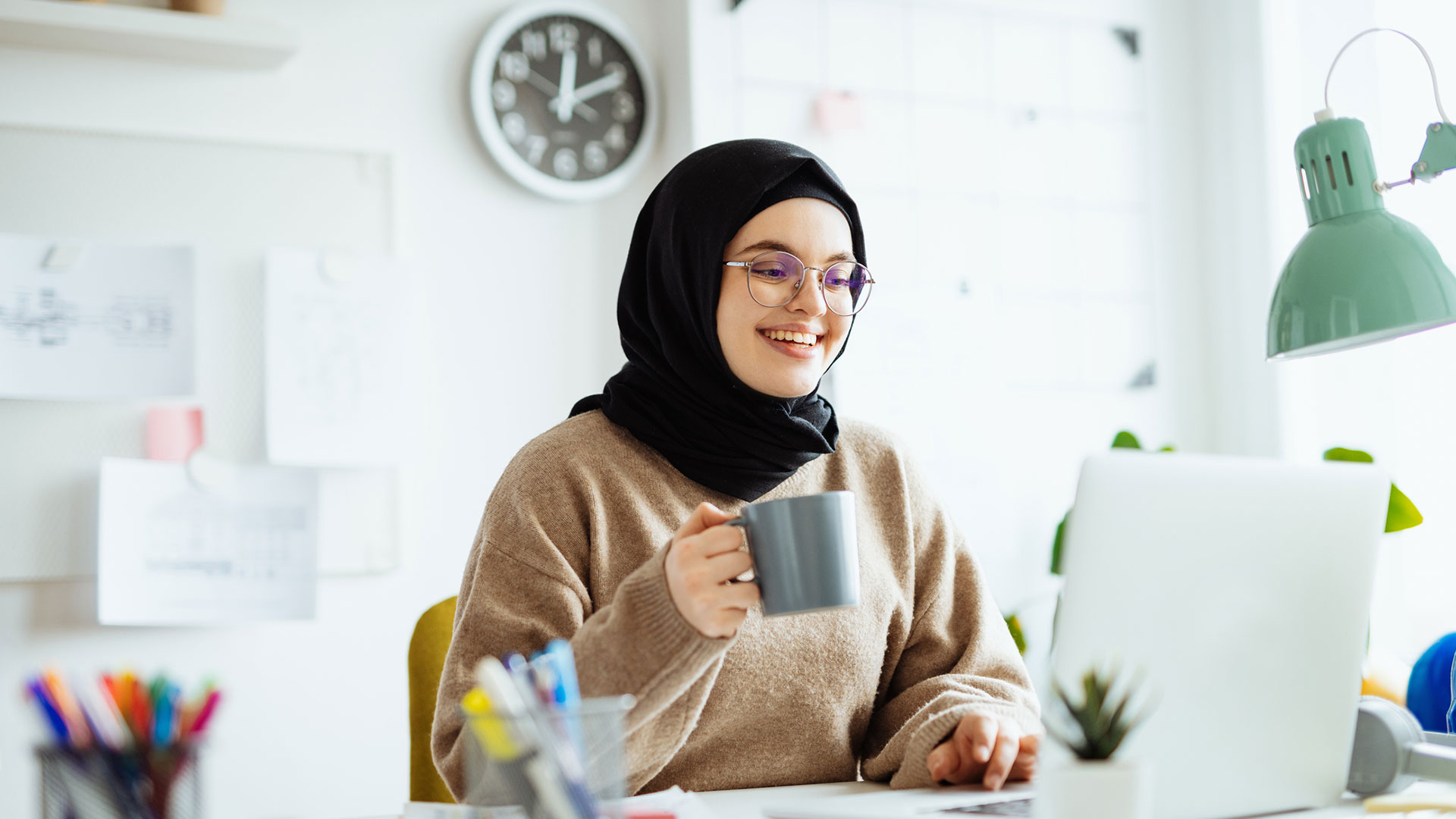 Middle Eastern woman with black hijab working on laptop in office