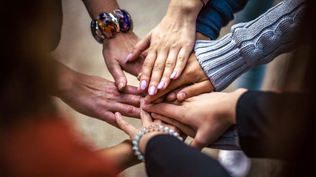Closeup shot of an unrecognisable group of people joining their hands together in a huddle