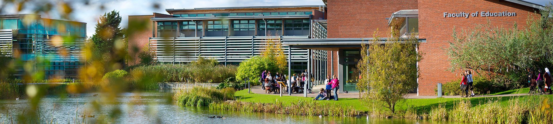 People sitting outside the faculty of education building, next to the lake