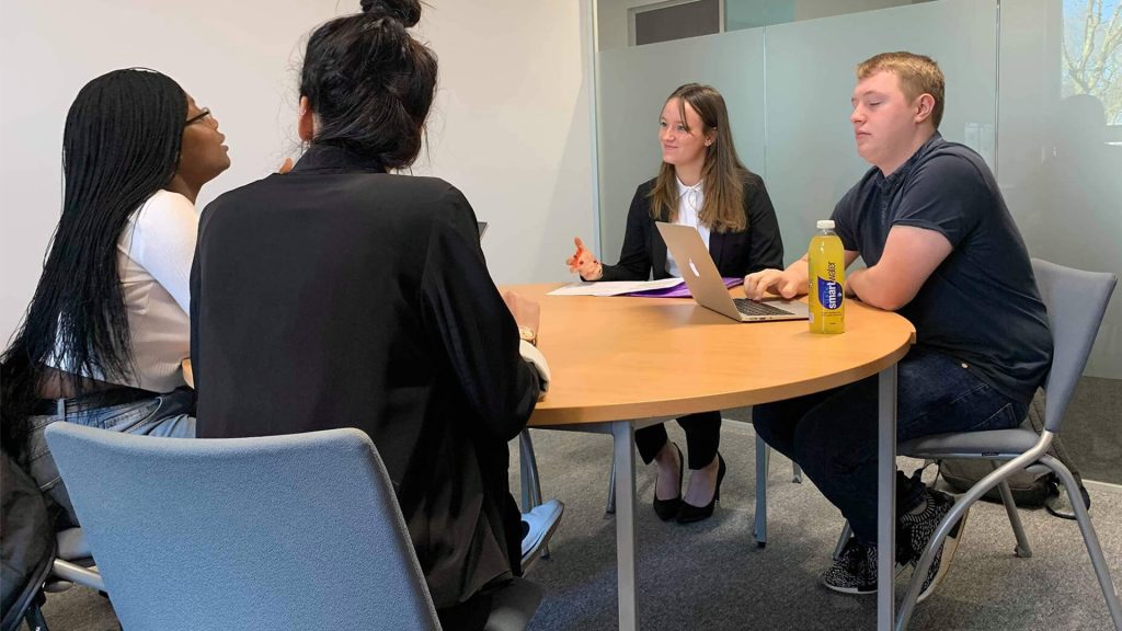 Four students sit around a table in discussion at the law clinic