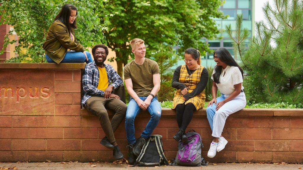 A group of students sit outside laughing and talking