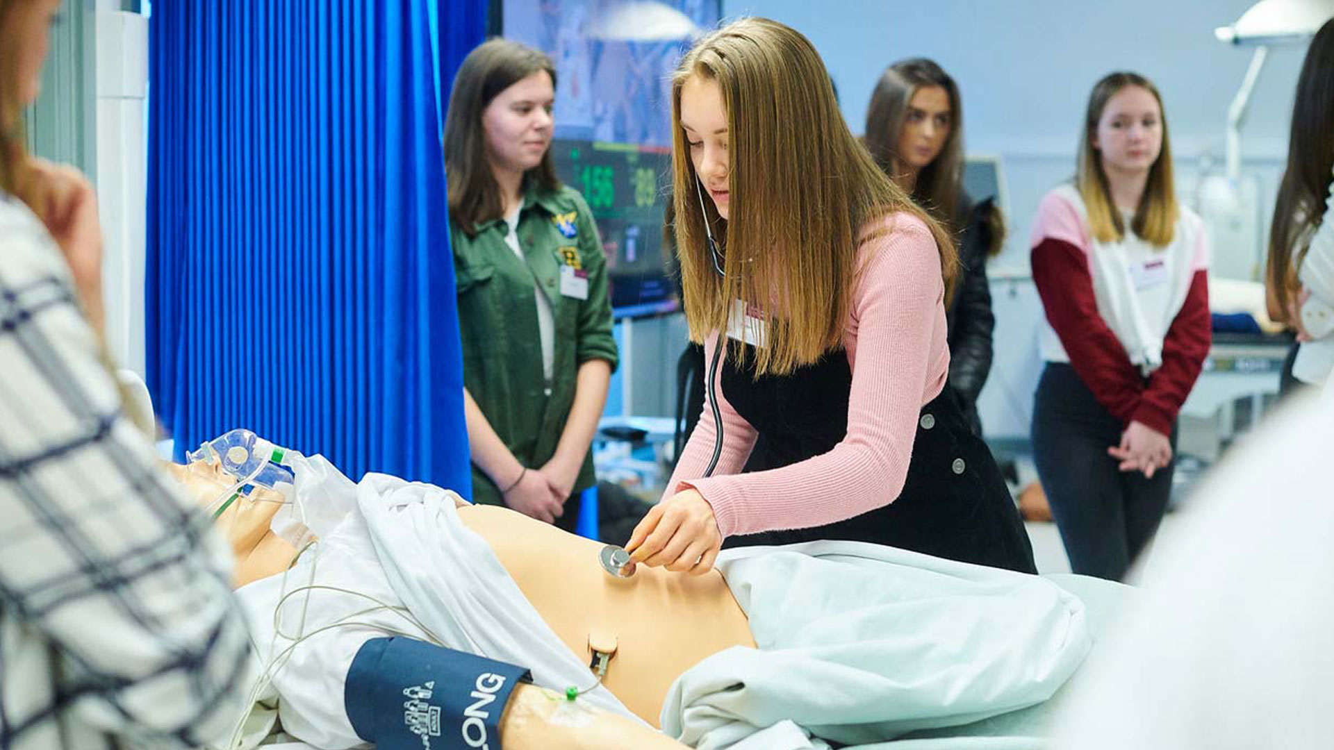 Medical student working on a dummy, whilst other students watch