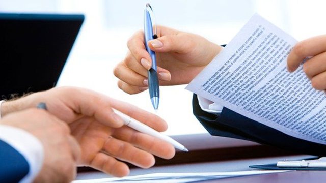 A close up of two people's hands, holding pens with paper in front of them