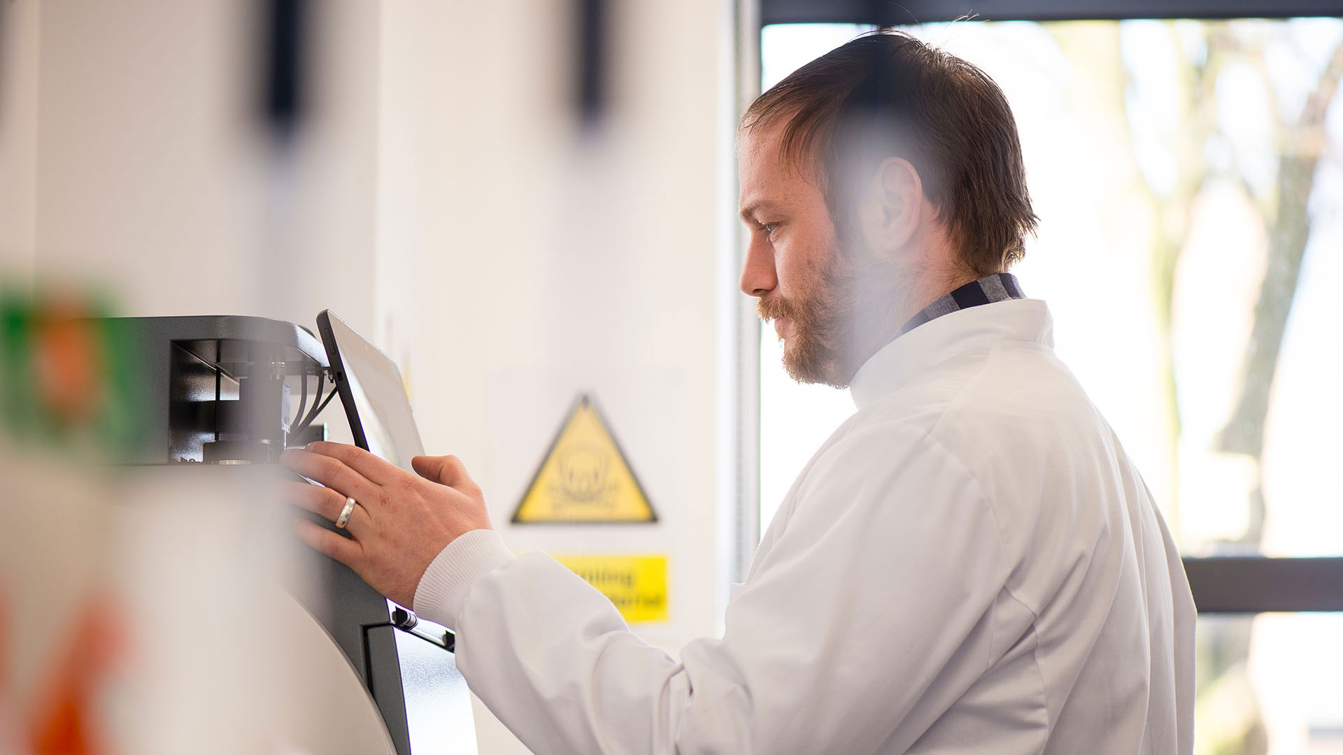 Man wearing a lab coat pressing a button on a machine