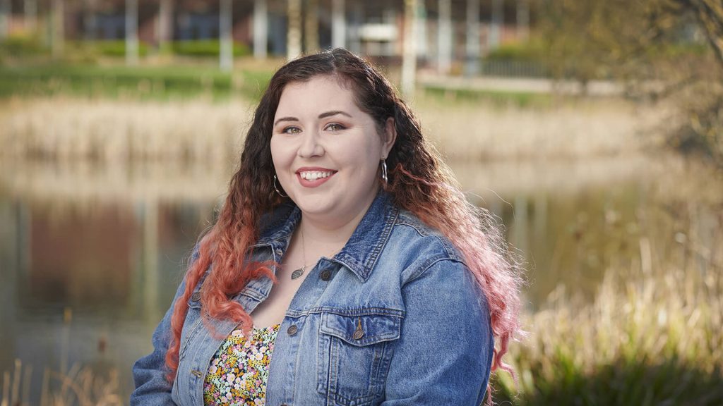 BSc (Hons) Psychology 2019 graduate, Robyn Ashfield, in front of a lake on campus. 