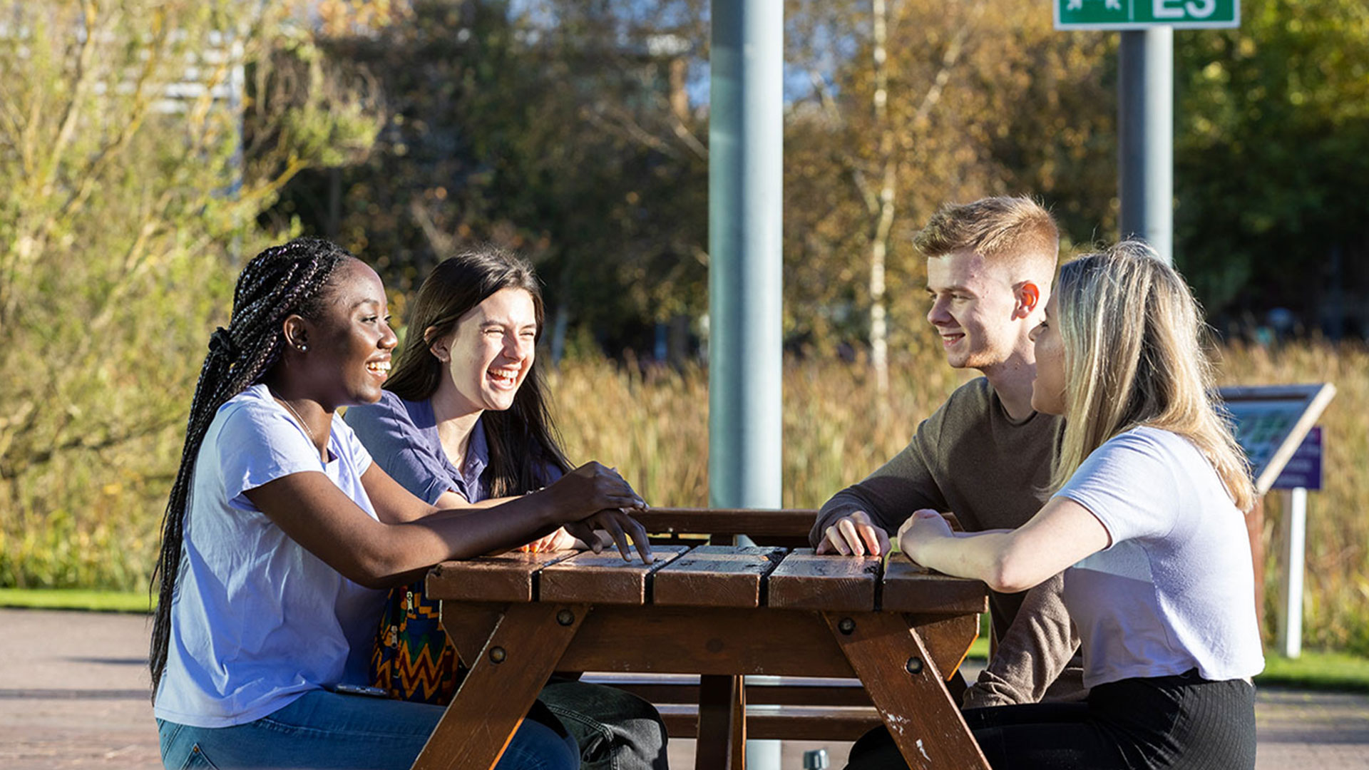 Students sitting outside on a picnic bench laughing