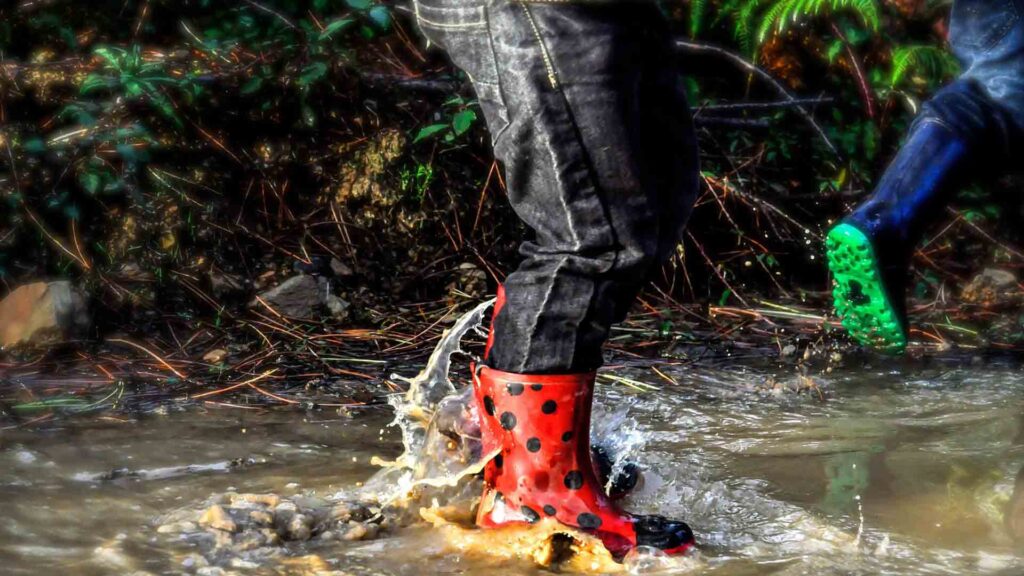Child in red wellies jumping in a river
