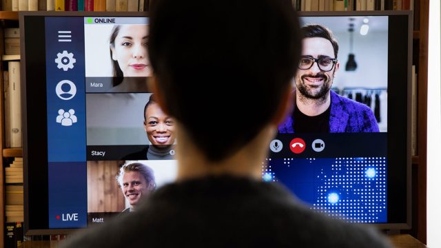 Unrecognisable person sitting in front of a computer screen taking part in a video call