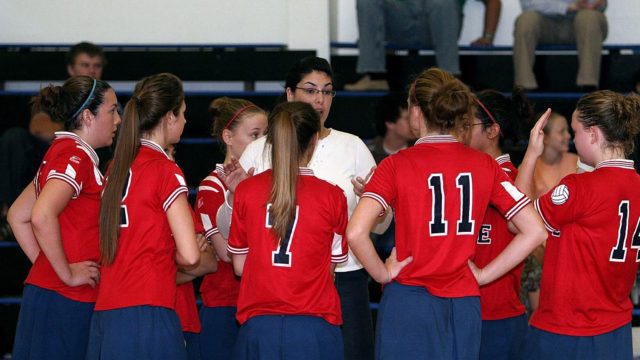 Vollyball team crowded round their coach at half time of their game