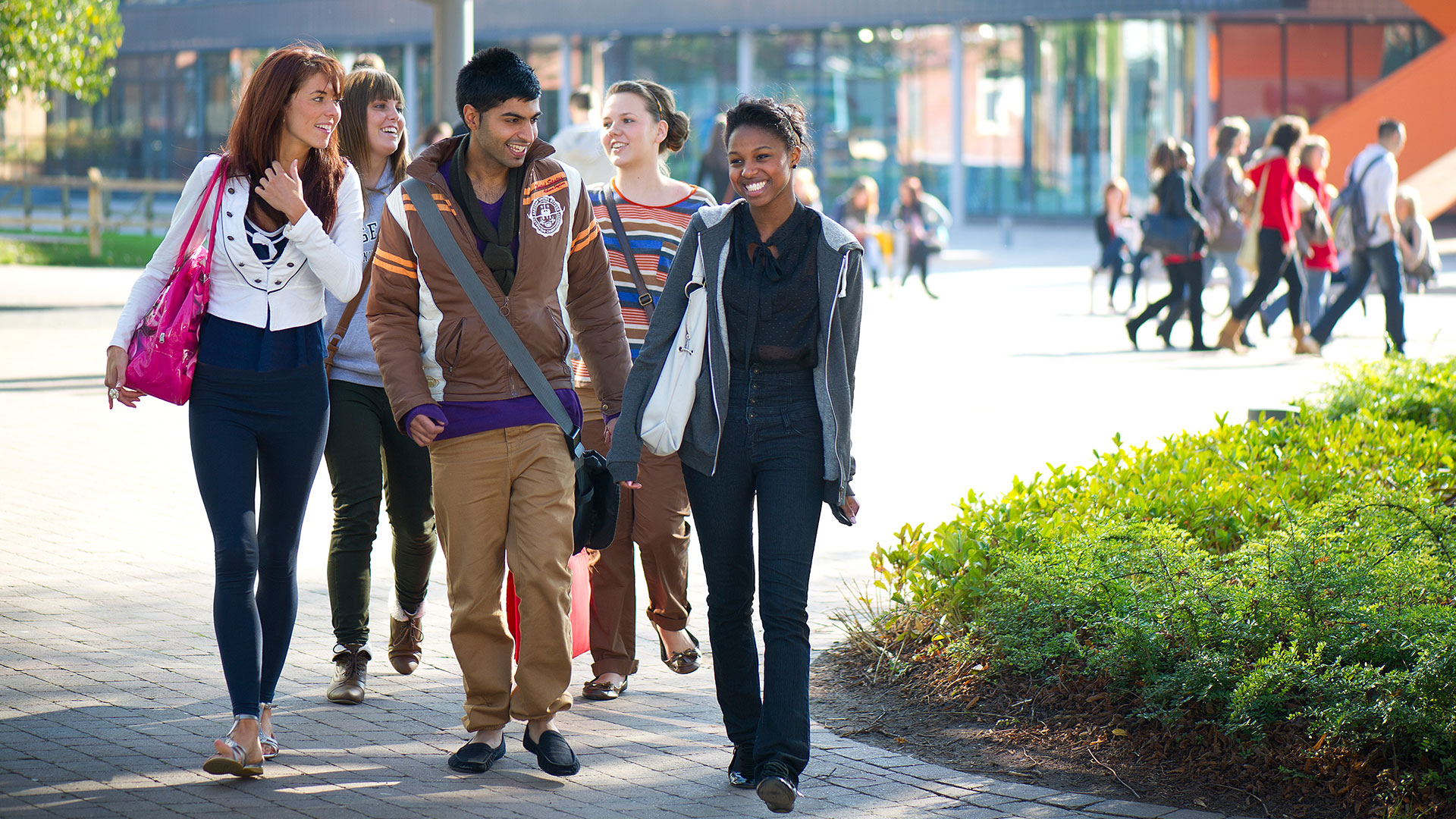 Students walking through campus, smiling and talking to each other