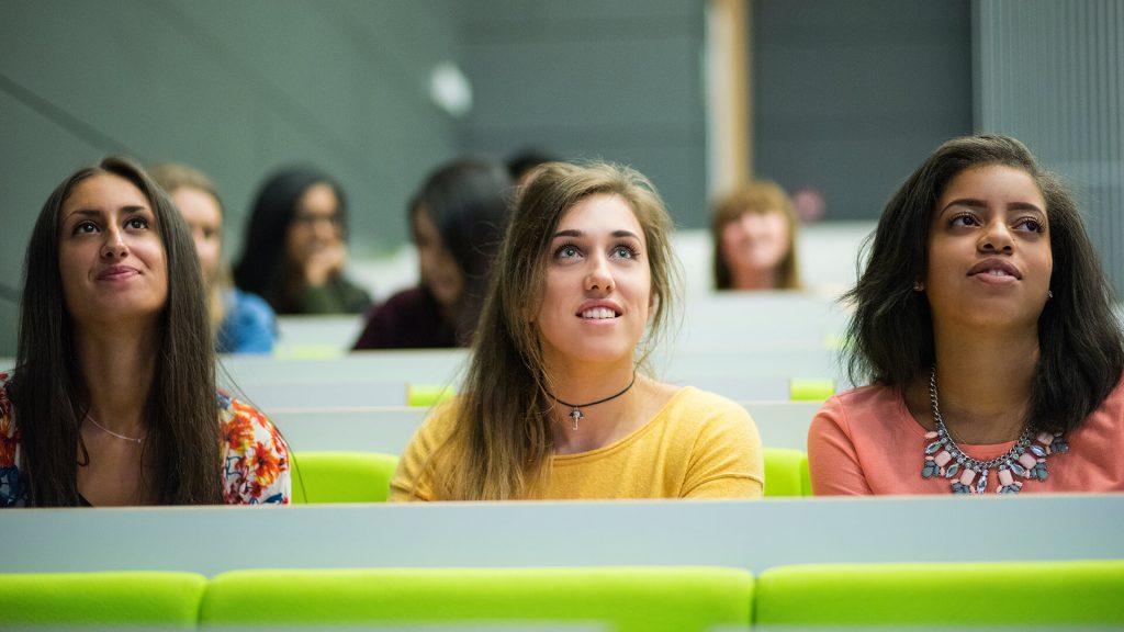 Three students listen attentively during a lecture in the Business School.