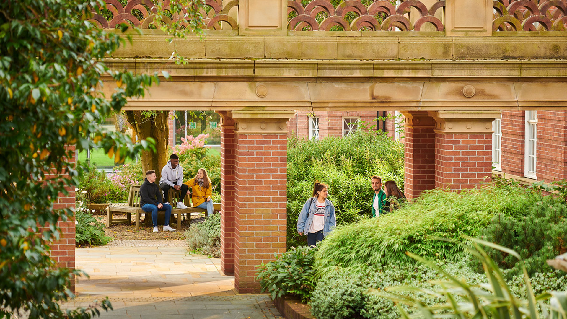 Students sitting in the main building garden area whilst other students walk past