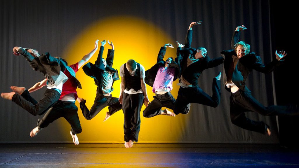 A group of dancers jump in the air in the arts centre theatre