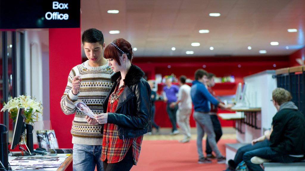 Students looking a brochure at the box office in the Arts Centre.