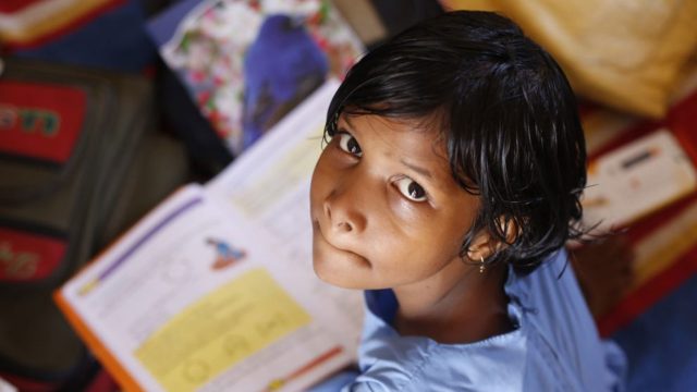 Young child looking up at the camera with a book on the table in front of him