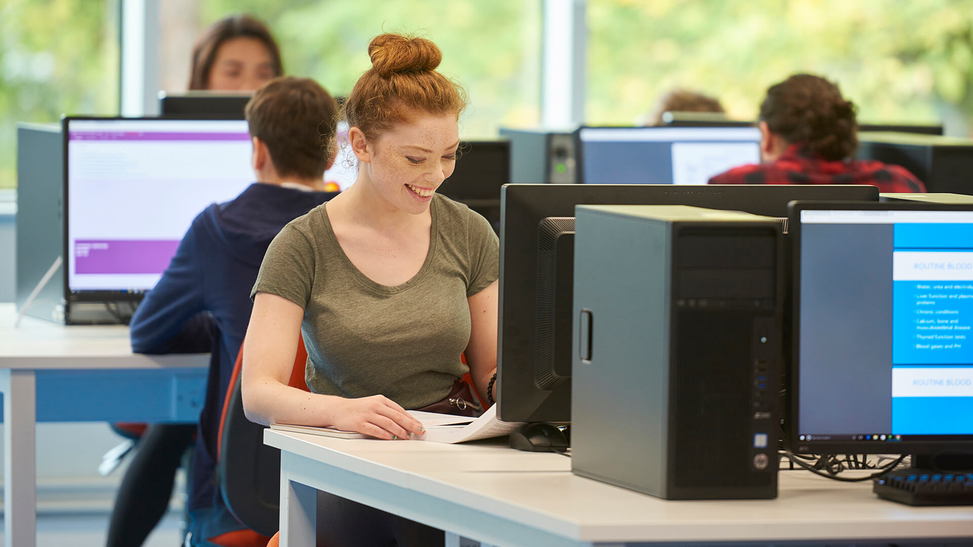 A student reads notes in a computer laboratory in the Tech Hub.