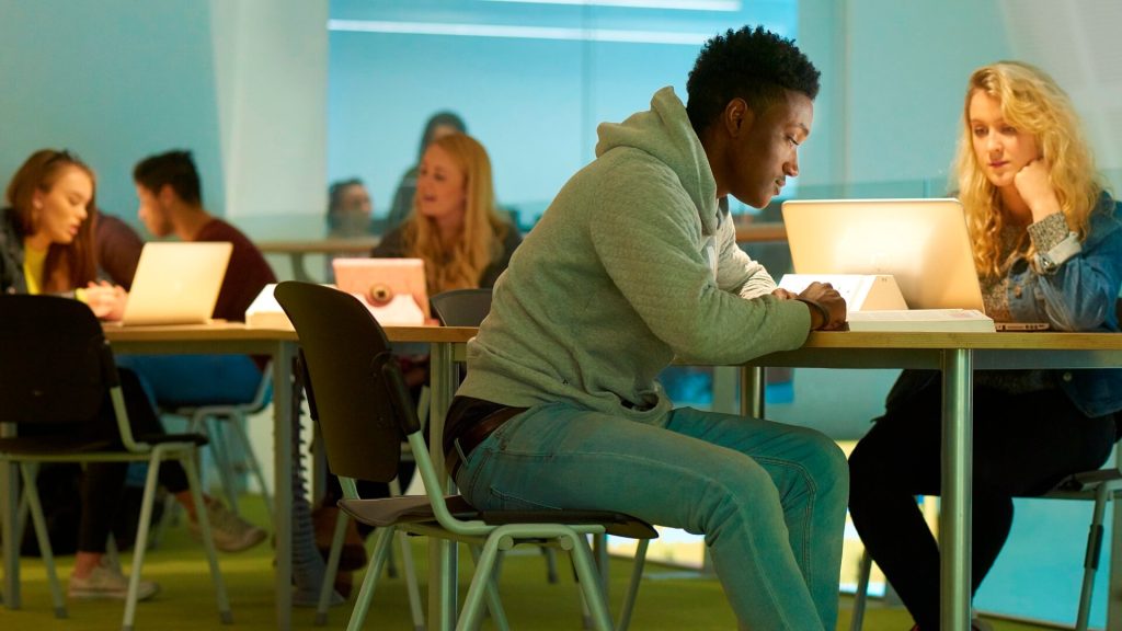 Students sit round tables working in one of the social learning areas in the Tech Hub.