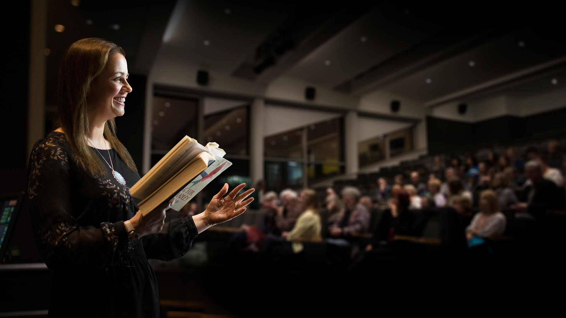 A writer reads an extract of their work to a lecture theatre of Creative Writing students.