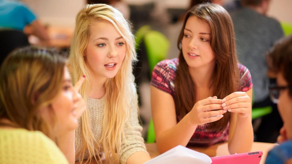 Three students participate in a group discussion during a seminar.