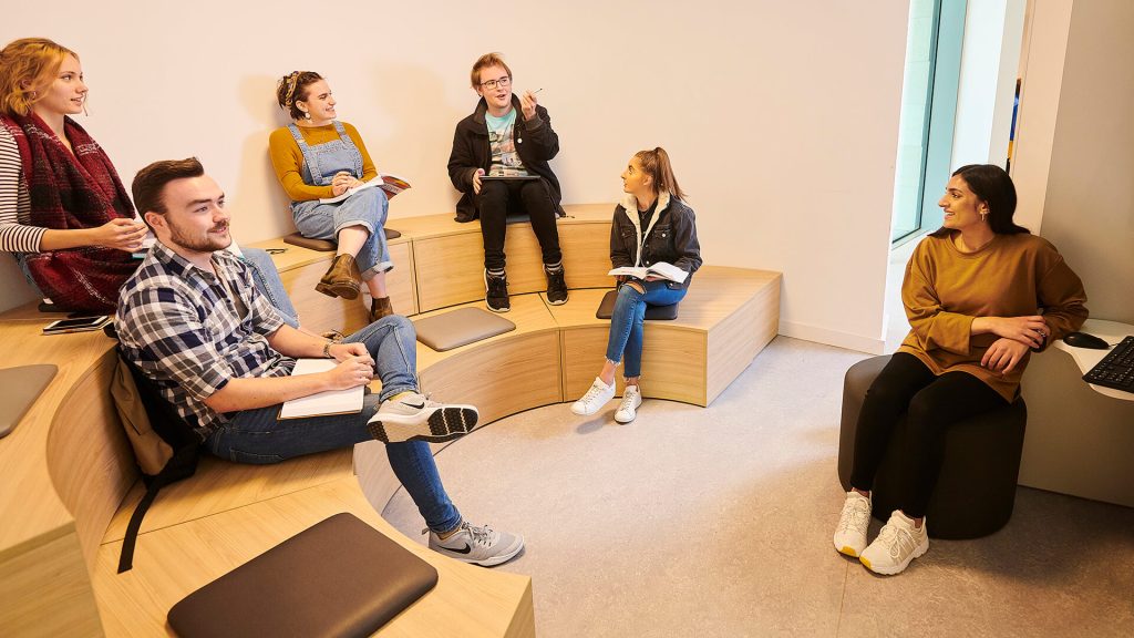 Six students talk in a group study space in the Catalyst building.