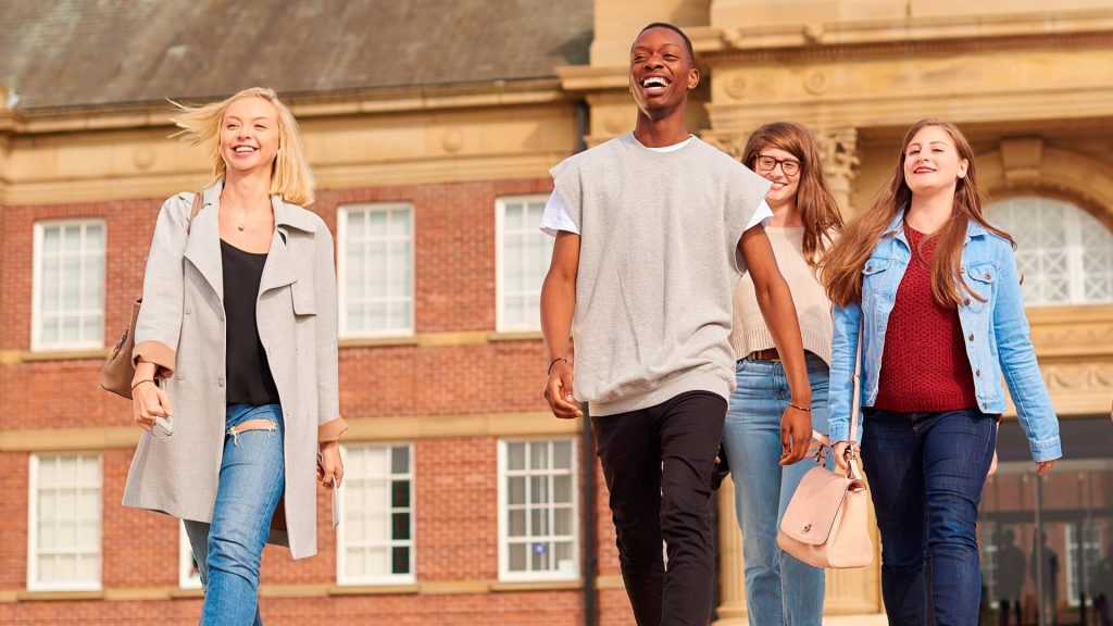 Four students walking out the front entrance to the Main Building.