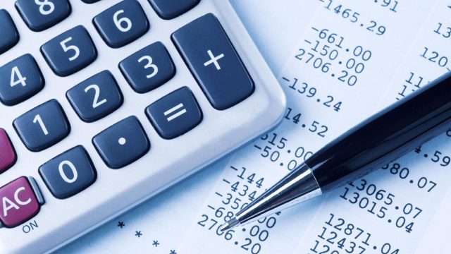 Close up of a calculator, finance receipt with figures and a pen