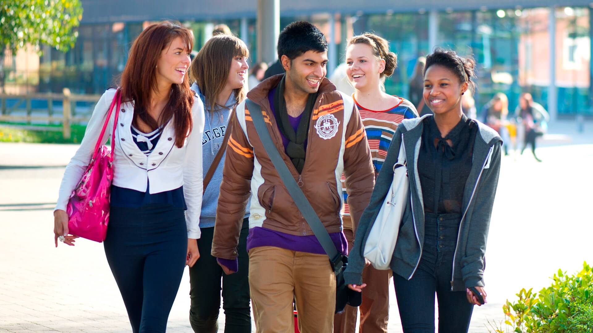 A group of students walking past the Business School with the Hub in the background.