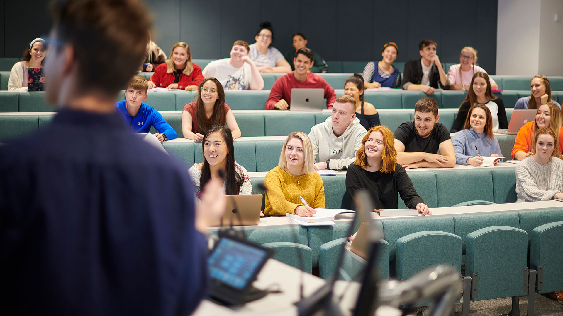 A lecturer addresses students in a Harvard-style lecture theatre.