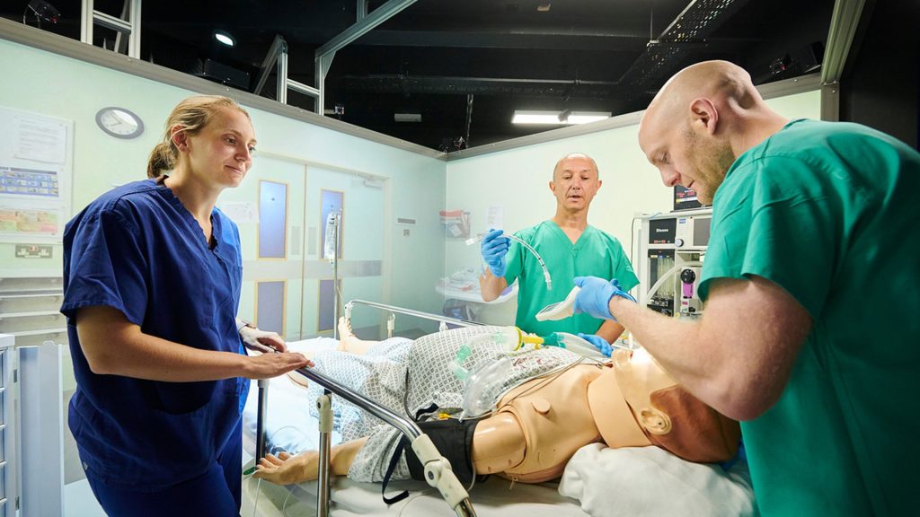 Three medical students performing a surgery procedure on a mannequin in the St James' campus Clinical Skills Centre