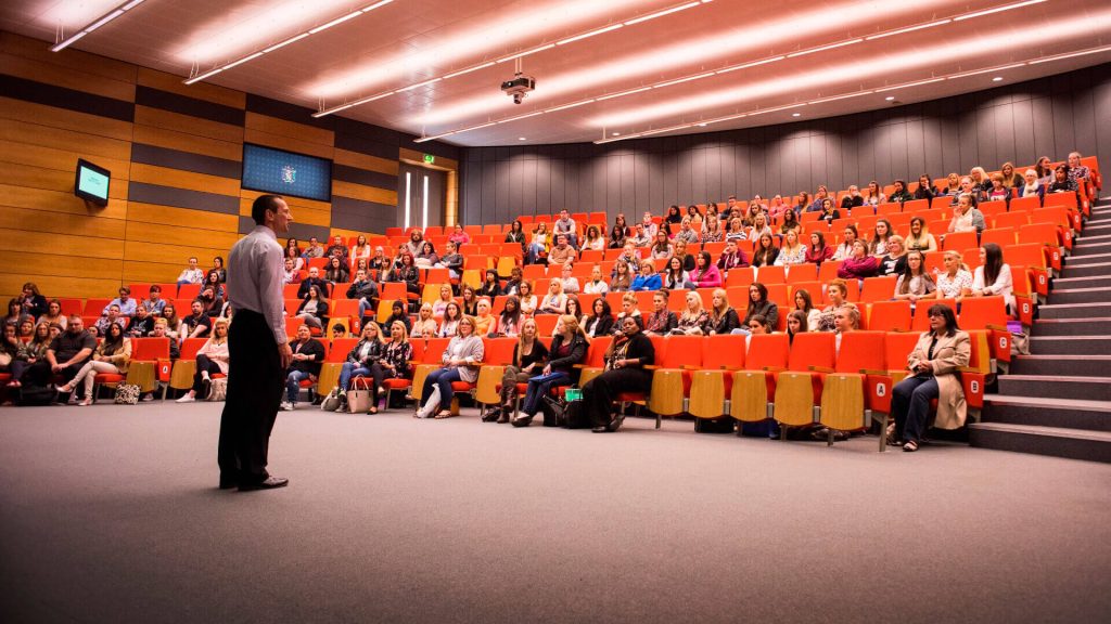 A lecturer addresses a large lecture theatre of students in the Faculty of Health, Social Care and Medicine.