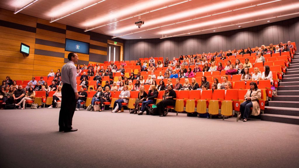 A lecturer addresses a large lecture theatre of students in the Faculty of Health, Social Care and Medicine.