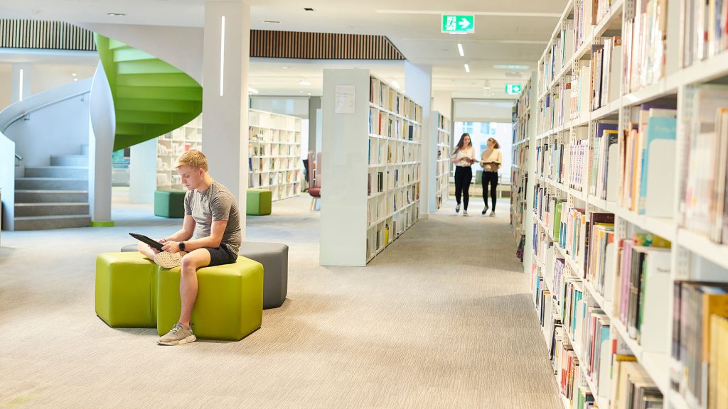 A student consults their tablet in the University library.