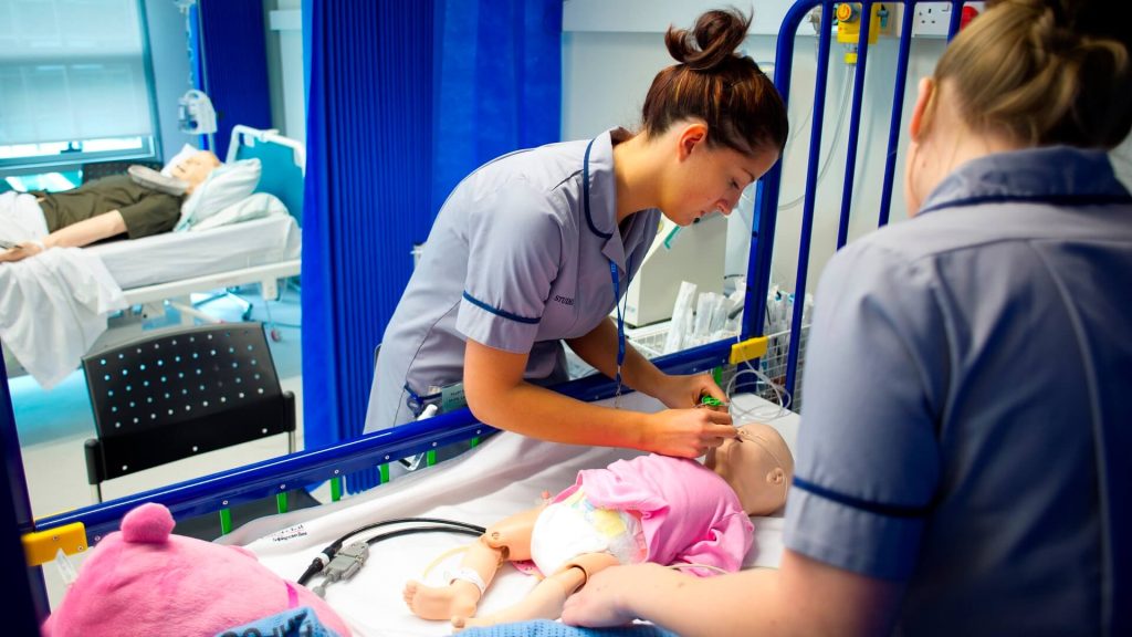 Two student nurses assess a poorly baby.