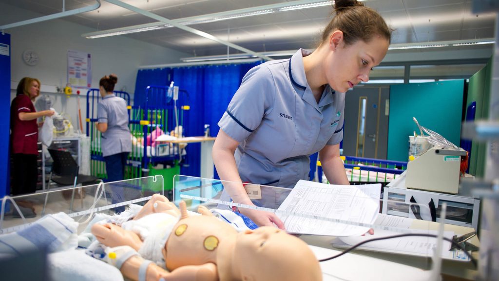 A student nurse practices administering medication to a baby.