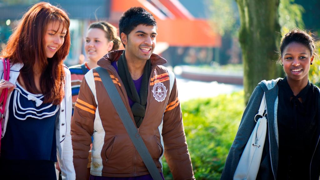 A group of students walk near the Hub towards the western side of campus.