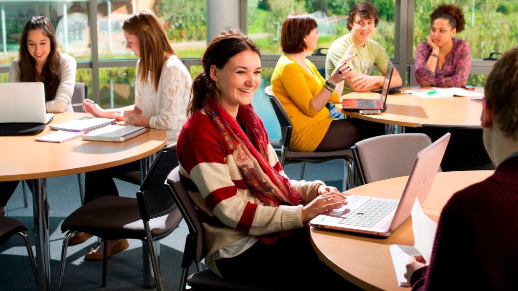 Seven students sit around three tables in a seminar room in the Faculty of Health, Social Care and Medicine.