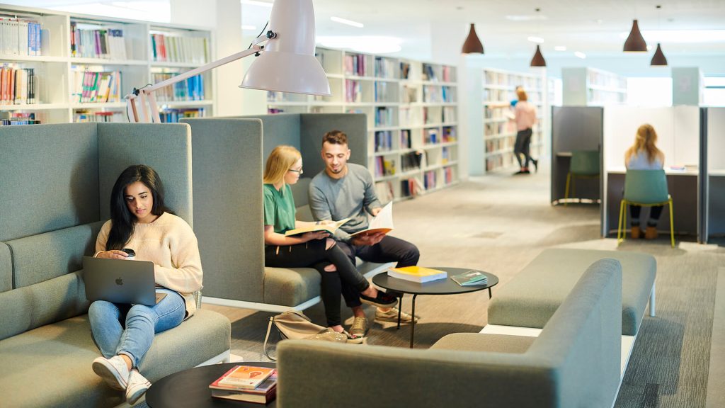 A student works on a laptop in the Catalyst building while sat on a sofa.