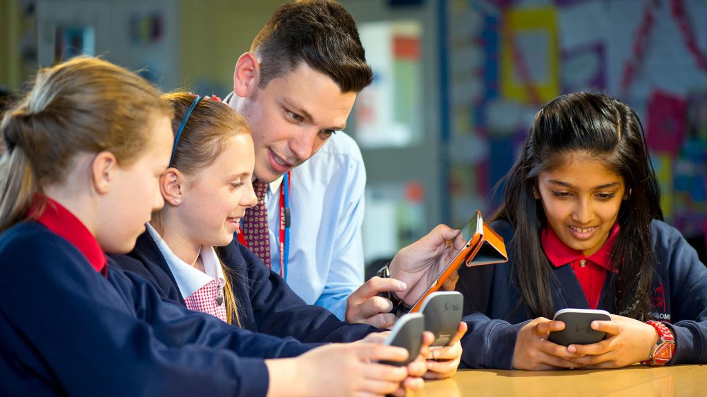 A primary school teacher sits with pupils during a maths lesson.