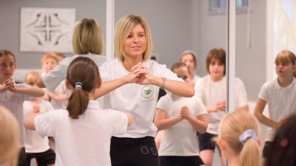 A primary teacher leads a physical education class in school.